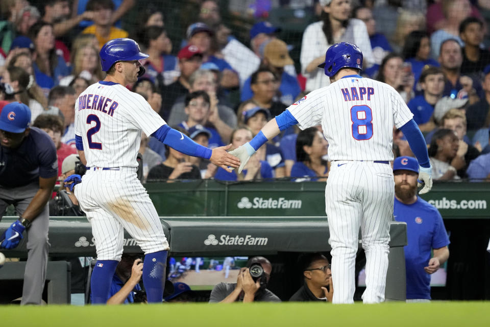 Chicago Cubs' Nico Hoerner (2) greets Ian Happ outside the dugout after Hoerner scored on Happ's sacrifice fly during the third inning of a baseball game Monday, July 31, 2023, in Chicago. (AP Photo/Charles Rex Arbogast)