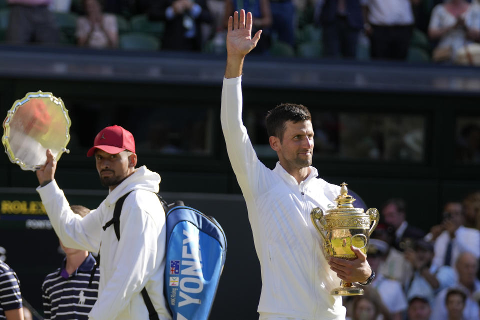 Serbia's Novak Djokovic, right, holds the winners trophy as he celebrates after beating Australia's Nick Kyrgios, left, to win the final of the men's singles on day fourteen of the Wimbledon tennis championships in London, Sunday, July 10, 2022. (AP Photo/Alastair Grant)