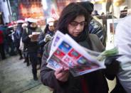 People line up and read the sales flyer outside a Toys"R"Us store in Times Square before their Black Friday Sale in New York November 28, 2013. REUTERS/Carlo Allegri