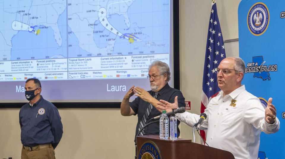 As GOHSEP Director Jim Waskom, left, watches, and Dr. Daniel Burch does sign interpretation, center, Gov. John Bel Edwards answers questions while holding a media briefing about the state's activity related to Hurricanes Marco and Laura, in addition to hosting a Unified Command Group meeting afterwards. Both storms are forecast to impact Louisiana this week within a few days of each other Monday August 24, 2020, in Baton Rouge, La. (Bill Feig/The Advocate via AP) (Bill Feig./The Advocate via AP)