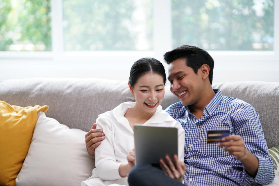 Portrait of Young Asian Couple relaxing in living room using tablet shopping online simple lifestyle in modern family