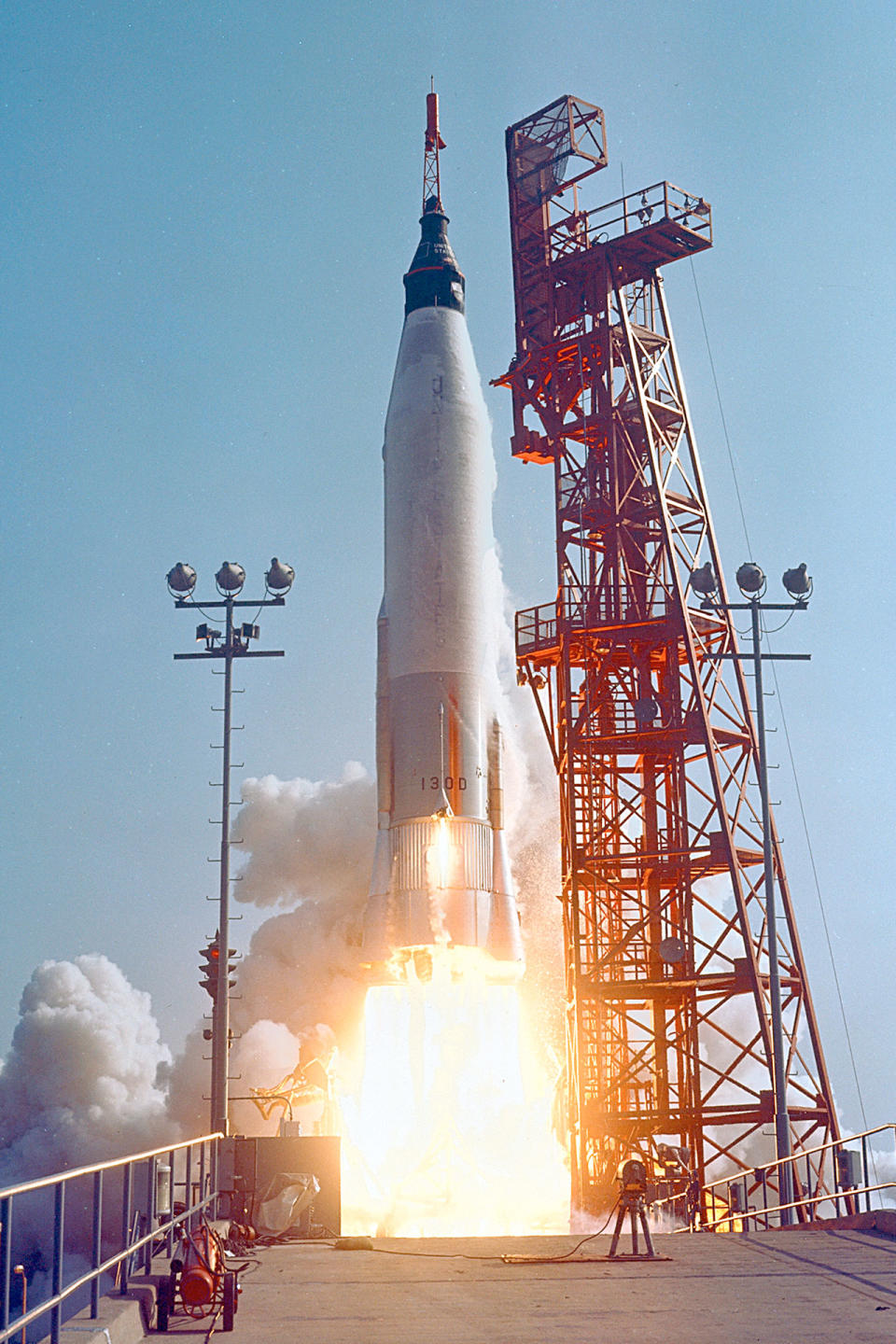 close-up photo of a white rocket launching into the blue sky