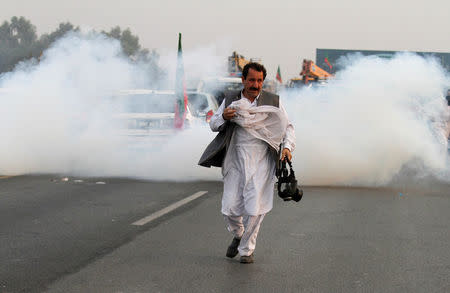 A supporter of Pakistani opposition leader Imran Khan runs from tear gas during clashes between police and protesters in Swabi, between Peshawar and Islamabad, Pakistan October 31, 2016. REUTERS/Fayaz Aziz