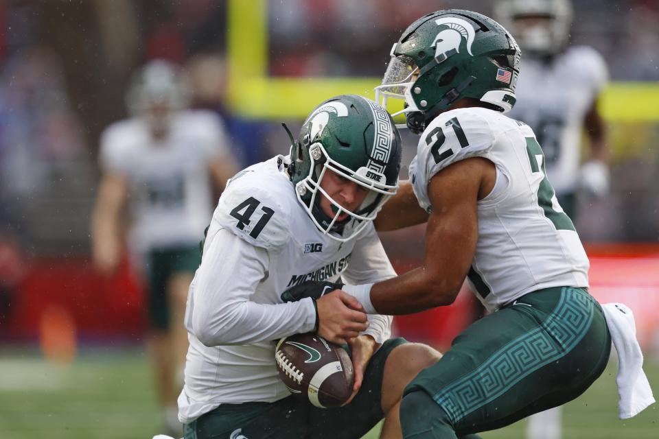 Derrick Harmon of the Michigan State Spartans is helped up by Dillon Tatum of the after recovering a fumble on a punt return by Shaquan Loyal of the Rutgers Scarlet Knights during the second quarter of a game at SHI Stadium on October 14, 2023 in Piscataway, New Jersey.