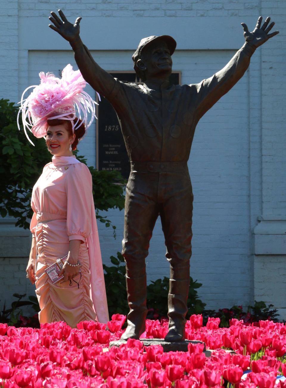 Carrie Ketterman of Corydon Ind, walks by the Pat Day statue in the Paddock garden, wearing a dress inspired by Lucille Ball in the movie “Ziegfelds Follies.”