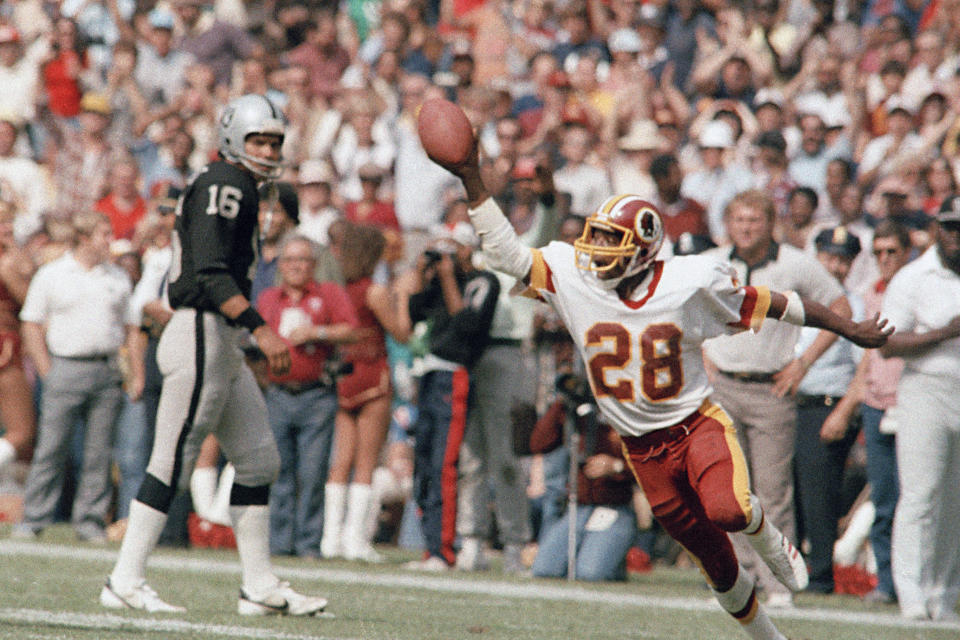 FILE - Washington Redskins Darrell Green (28) is shown in action during an NFL football game against the Los Angeles Raiders in Washington, Oct. 2, 1983. At left is Raiders quarterback Jim Plunkett. The Washington Commanders are retiring Hall of Fame cornerback Darrell Green's No. 28 next season, the latest step in the organization's efforts to honor players of the past since new ownership took over last summer. The team announced Thursday, April 25, 2024, that Green will be the fifth player in franchise history to receive that honor. (AP Photo/Pete Wright, File)