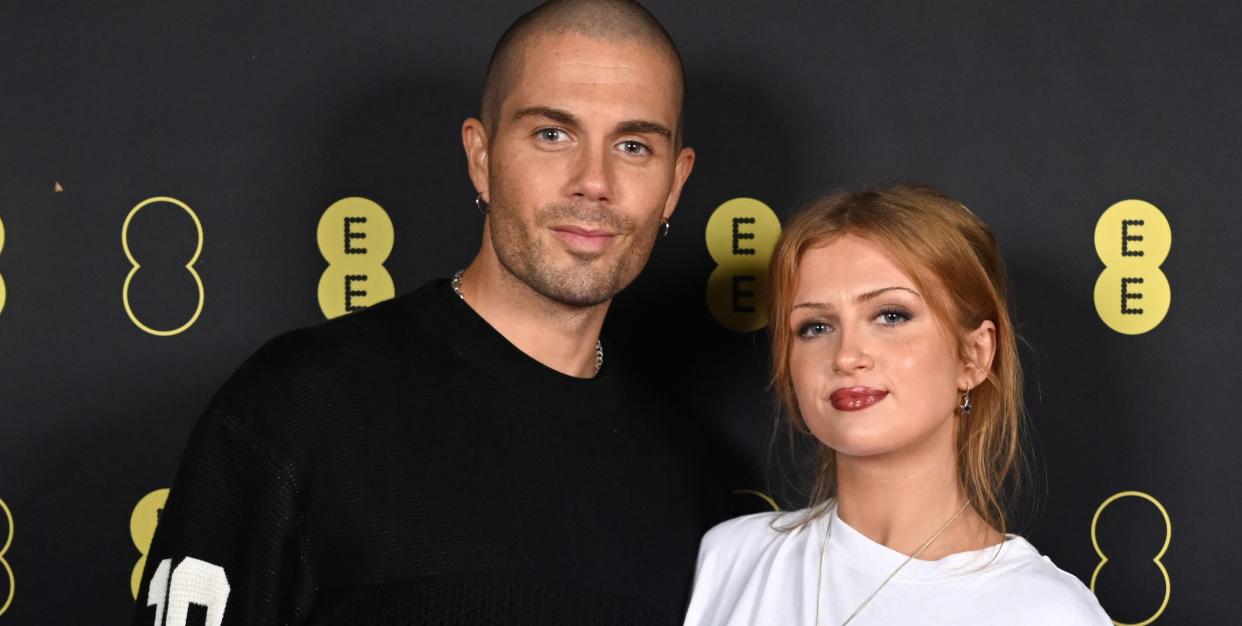 max george and maisie smith, a couple stand looking at the camera slightly smiling and wearing casual tshirts