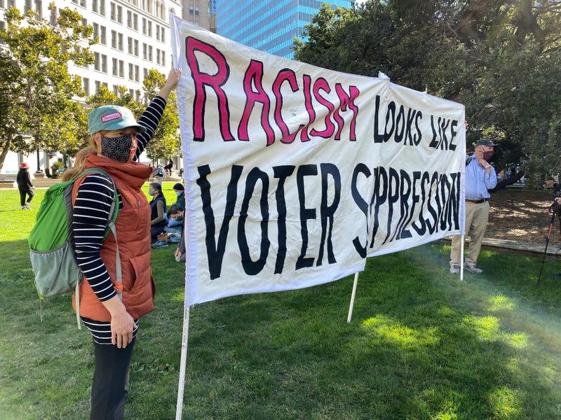 People hold a banner during a gathering to call for democracy and demand for every vote to be counted, in Oakland