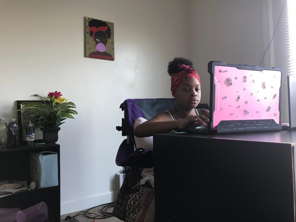 Kiymani Russell, a fourth-grader at Edison School of the Arts, attends class virtually from the living room of the Indianapolis apartment she lives in with her mom, Swantella Nelson, and 2-year-old brother Randy. Kiymani has decorated the school-provided laptop with stickers.