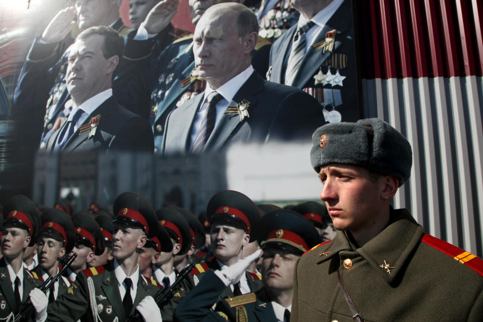 A Russian soldier stands in front of poster with portraits of Russian President-elect Vladimir Putin and outgoing President Dmitry Medvedev during a rehearsal for the Victory Day parade near Moscow on April 4, 2012. The parade is dedicated to the anniversary of the Soviet victory over Nazi Germany in World War II.