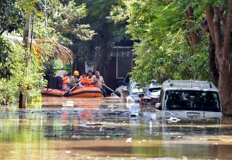 Members of a rescue team row their boat past submerged vehicles following torrential rains in Bengaluru