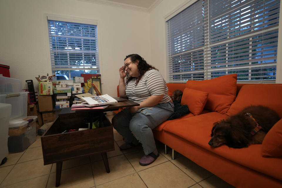 Krystal Guerra, 32, accompanied by her dogs Einstein, right, and Stella, does online coursework for a degree program in digital marketing, inside the apartment which she is packing up to leave after her new landlord gave her less than a month's notice that her rent would go up by 26%, Saturday, Feb. 12, 2022, in the Coral Way neighborhood of Miami. Guerra, who works in marketing while also pursuing a degree part-time, had already been spending nearly 50% of her monthly income on rent prior to the increase. Unable to afford a comparable apartment in the area as rents throughout the city have risen dramatically, Guerra is putting many of her belongings into storage and moving in with her boyfriend and his daughter for the time being. (AP Photo/Rebecca Blackwell)