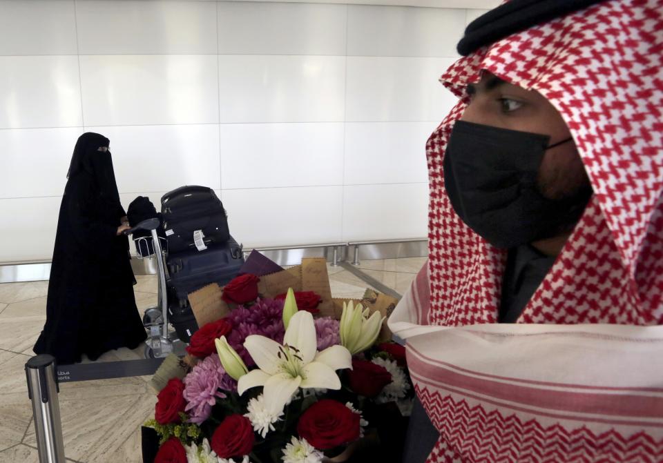 FILE - Saudi Bandar Al-Qahtani holds flowers as he waits for the arrival of his relatives on the first Qatar Airways plane in three years to land at King Khalid Airport in Riyadh, Saudi Arabia, Jan. 11, 2021. Qatar will be on the world stage like it never has before as the small, energy-rich nations hosts the 2022 FIFA World Cup beginning this November. (AP Photo/Amr Nabil, File)