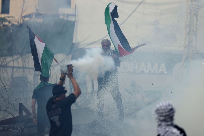 Varias personas sostienen banderas durante una protesta cerca de la embajada de Estados Unidos en Awkar, Líbano, tras la muerte de cientos de palestinos en una explosión en el hospital Al-Ahli de Gaza de la que se culparon mutuamente funcionarios israelíes y palestinos