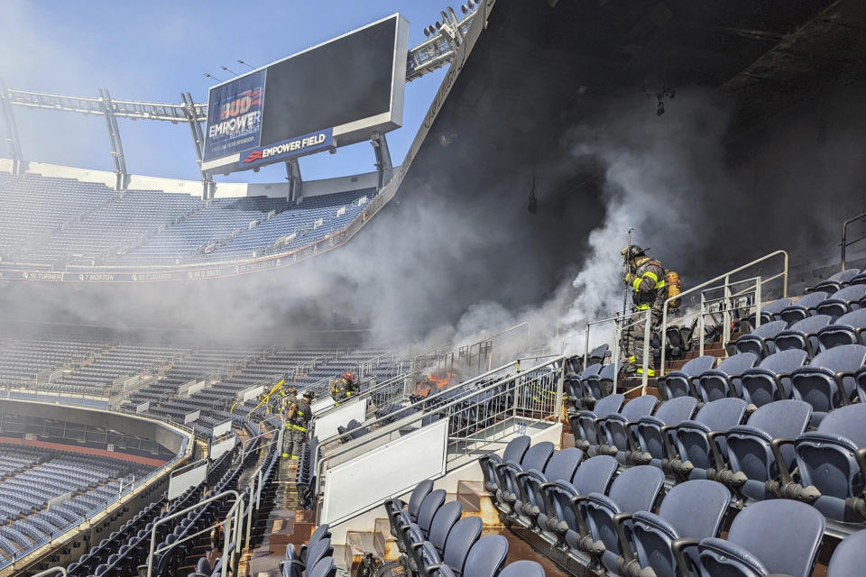 In this photo provided by the Denver Fire Department, firefighters battle a fire at Empower Field at Mile High stadium in Denver, Thursday, March 24, 2022. Firefighters have extinguished a blaze that torched several rows of seats and a suite area at the Denver Broncos' stadium. The fire broke out in the third-level and burned at least six rows of seats in two sections. (Denver Fire Department via AP)