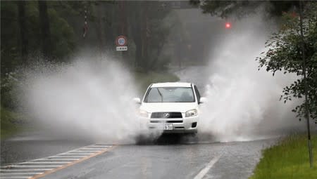 A car splashes through large puddles caused by downpours in Miyazaki, southwestern Japan