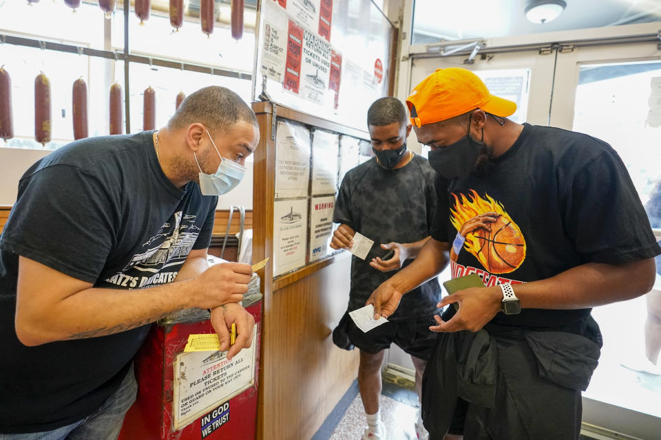 A Katz's Deli employee, left, checks the proof of vaccination from customers who will be eating inside the restaurant, Tuesday, Aug. 17, 2021, in New York. New York City is asking restaurants, gyms, museums and many other indoor venues to have patrons show proof of vaccination against COVID-19. The new rules are part of the city's latest campaign to control a pandemic that had crippled the city's economy. (AP Photo/Mary Altaffer)