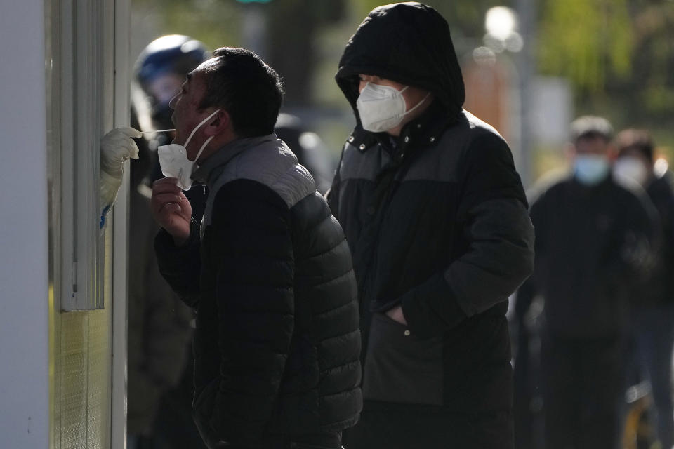 A man has his throat swabbed for a COVID-19 test at a testing site near the site of last weekend's protest in Beijing, Wednesday, Nov. 30, 2022. China's ruling Communist Party has vowed to "resolutely crack down on infiltration and sabotage activities by hostile forces," following the largest street demonstrations in decades staged by citizens fed up with strict anti-virus restrictions. (AP Photo/Andy Wong)