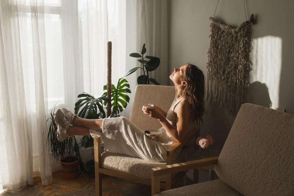 positive young female in casual clothes smiling while drinking herbal tea