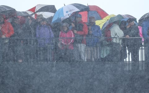 Spectators shelter from a severe rain shower during the first round of the 148th Open Championship held on the Dunluce Link - Credit: DAVID CANNON