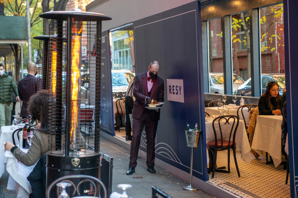 NEW YORK, NEW YORK - NOVEMBER 29: An employee wearing a mask lights a birthday candle outside an outdoor dining area at Carbone sponsored by American Express and Resy on November 29, 2020 in New York City. The pandemic continues to put a strain on restaurants and bars as businesses struggle to thrive with evolving government restrictions and social distancing plans impacting business continuity while threatening profitability. (Photo by Alexi Rosenfeld/Getty Images)