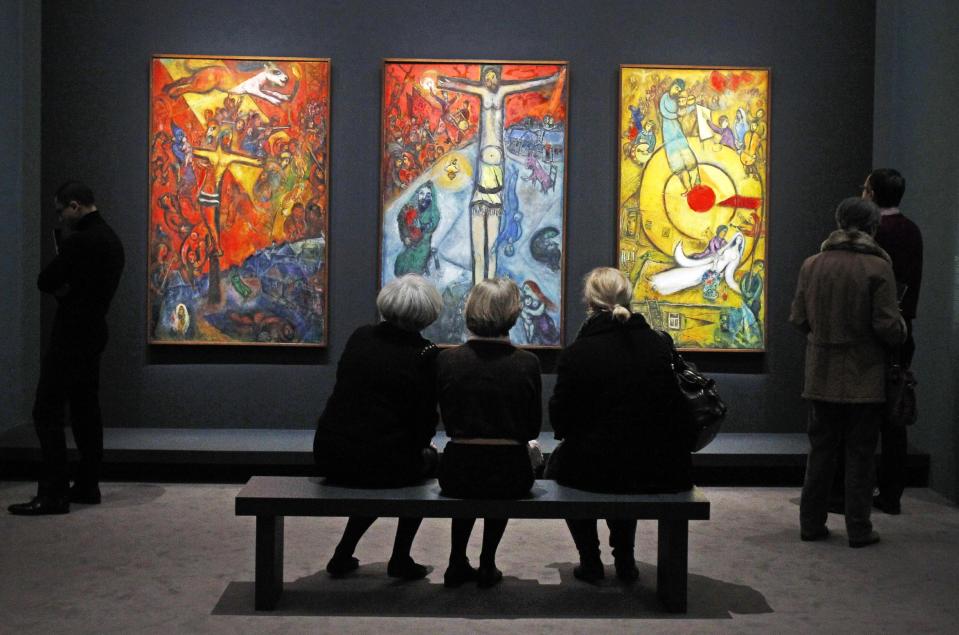 Members of the media view a triptych by Russian artist Marc Chagall before the opening of the exhibition: Chagall, between War and Peace, at the Luxembourg museum in Paris, Tuesday Feb. 19, 2013. The exhibition starts February 21 and ends July 21, 2013. Paintings are from left: 1937, Resistance, 1948, Resurrection, 1952, Liberation.(AP Photo/Remy de la Mauviniere)