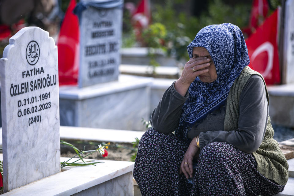 A woman sits next to a grave in a cemetery where some of the victims of the earthquake in Feb. 2023 are buried in Antakya, southern Turkey, Tuesday, Feb. 6, 2024. Millions of people across Turkey on Tuesday mourned the loss of more than 53,000 friends, loved ones and neighbors in the country's catastrophic earthquake a year ago. (AP Photo/Metin Yoksu)