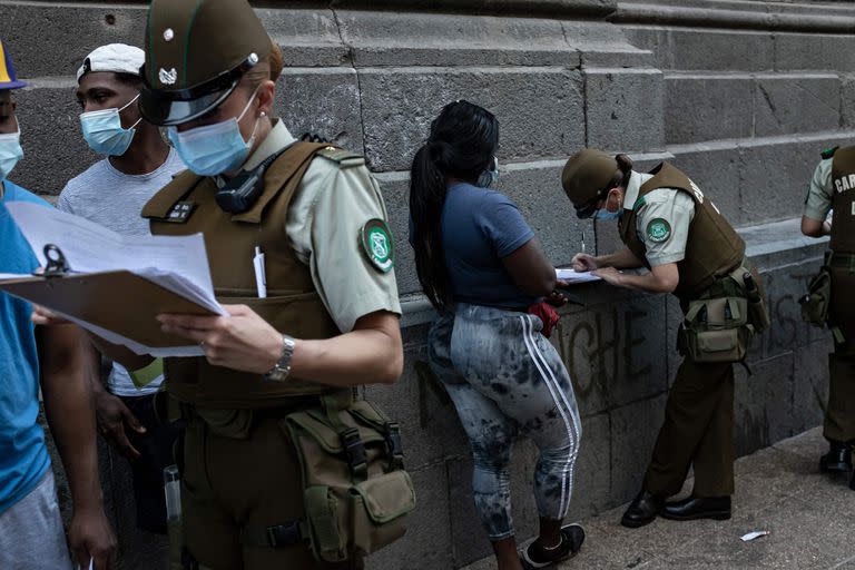 Los carabineros controlan la documentación de los migrantes que aguardan para regularizar su situación