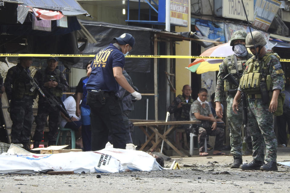 Police investigators examine the site after two bombs exploded outside a Roman Catholic cathedral in Jolo, the capital of Sulu province in southern Philippines, Sunday, Jan. 27, 2019. Two bombs minutes apart tore through a Roman Catholic cathedral on a southern Philippine island where Muslim militants are active, killing at least 20 people and wounding more than 80 others during a Sunday Mass, officials said. (AP Photo/Nickee Butlangan)