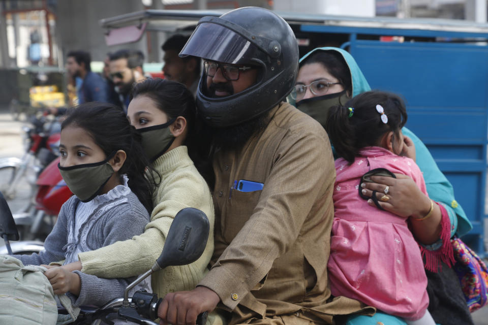 A Pakistani family wears face masks to help prevent exposure to the new coronavirus as they travel on a motorbike in Lahore, Pakistan, Monday, March 16, 2020. For most people, the new coronavirus causes only mild or moderate symptoms. For some it can cause more severe illness. (AP Photo/K.M. Chaudhry)