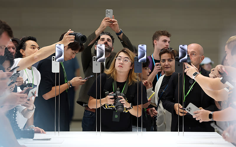 Attendees look at the new iPhone 15 during a Sept. 12 Apple event at the Steve Jobs Theater at Apple Park in Cupertino, Calif. Apple revealed its lineup of the latest iPhone 15 versions as well as other product upgrades during the event. <em>Justin Sullivan/Getty Images</em>