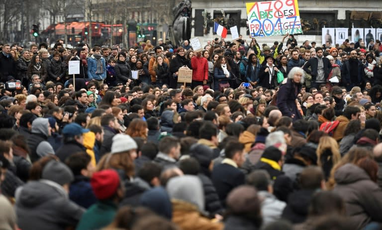 French protestor Jean-Baptise Redde (rear C), aka Voltuan, holds a placard reading "Cut out the benefits of corruption" during a rally to protest against the corruption of the elected representatives on February 19, 2017