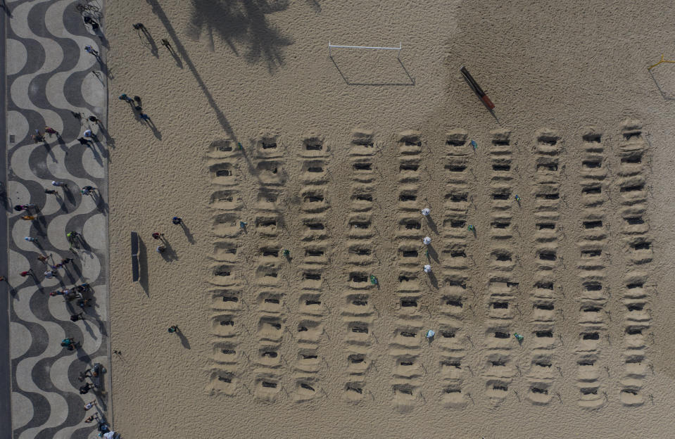 Activists dig symbolic graves on Copacabana beach as a protest, organized by the NGO Rio de Paz, against the government's handling of the COVID-19 pandemic in Rio de Janeiro, Brazil, Thursday, June 11, 2020. A Brazilian Supreme Court justice ordered the government of President Jair Bolsonaro to resume publication of full COVID-19 data, including the cumulative death toll, following allegations the government was trying to hide the severity of the pandemic in Latin America’s biggest country. (AP Photo/Leo Correa)