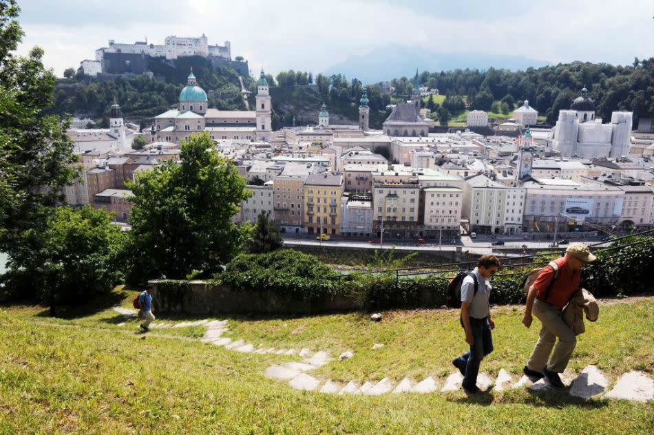 Hikers on capuchin hill with Fortress Hohensalzburg and the old town center in the background can be seen.