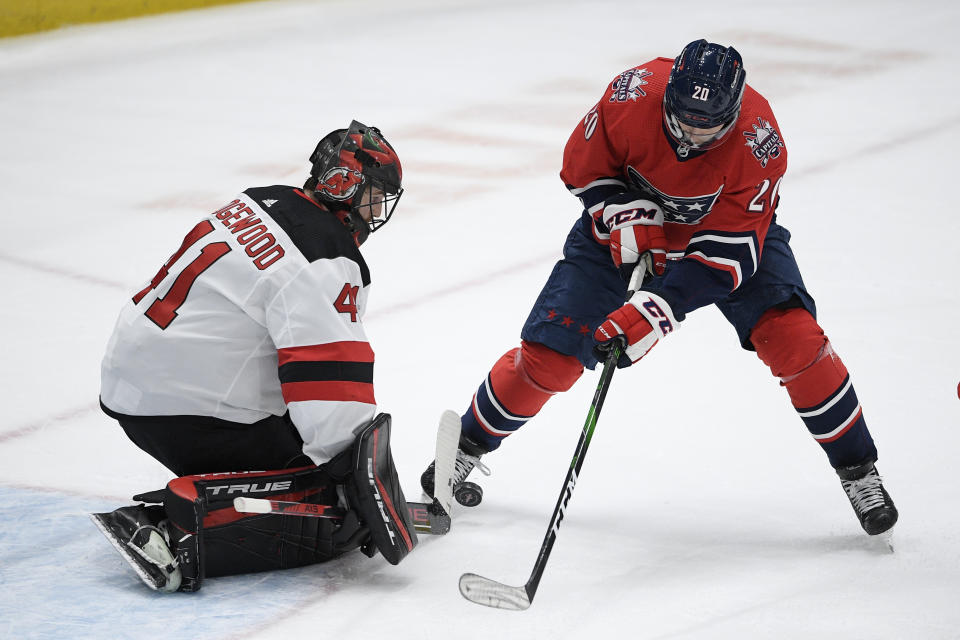 New Jersey Devils goaltender Scott Wedgewood (41) stops the puck next to Washington Capitals center Lars Eller (20) during the first period of an NHL hockey game Tuesday, March 9, 2021, in Washington. (AP Photo/Nick Wass)