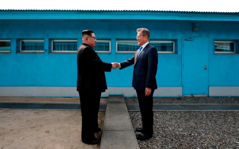 Kim Jong-un and Moon Jae-in shake hands at the inter-Korean border at the start of their first meeting in June - Credit: AFP/AFP 