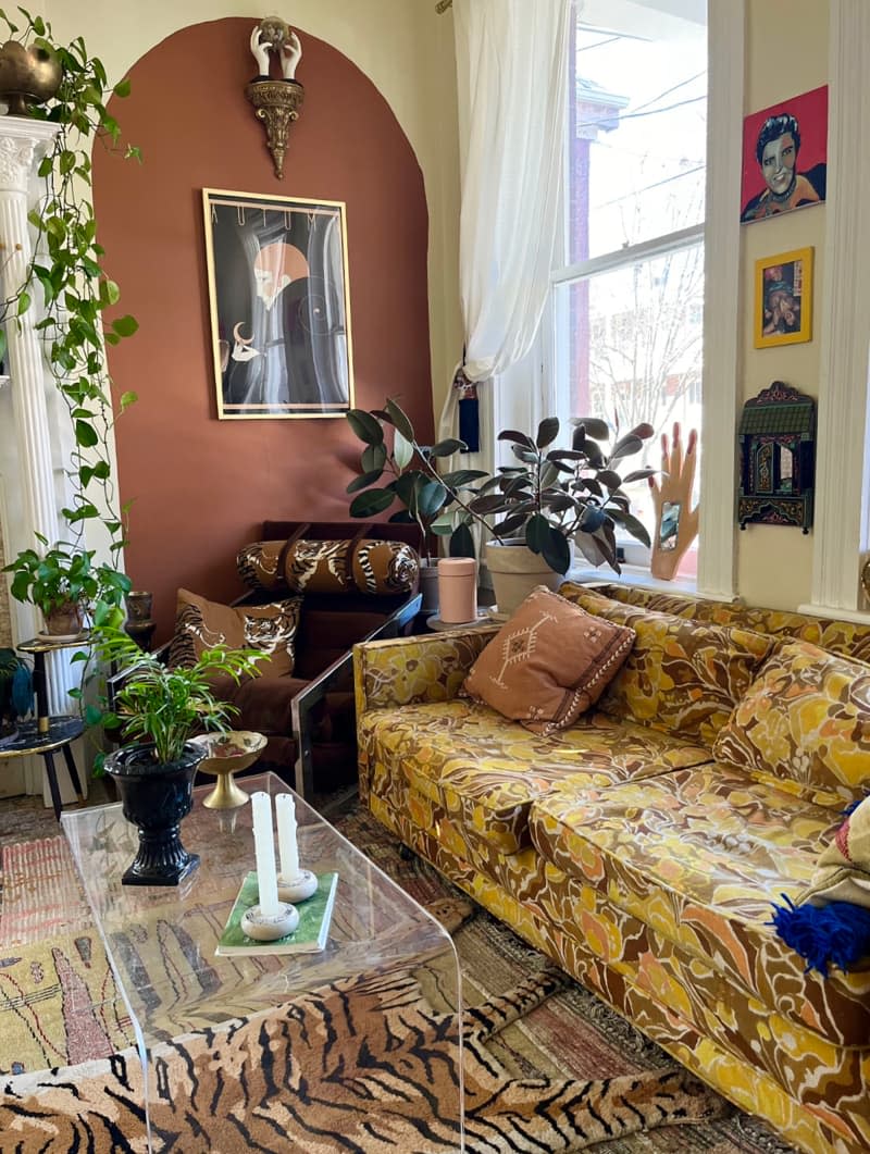 Patterned couch in record room with dark pink accent wall diplaying art.