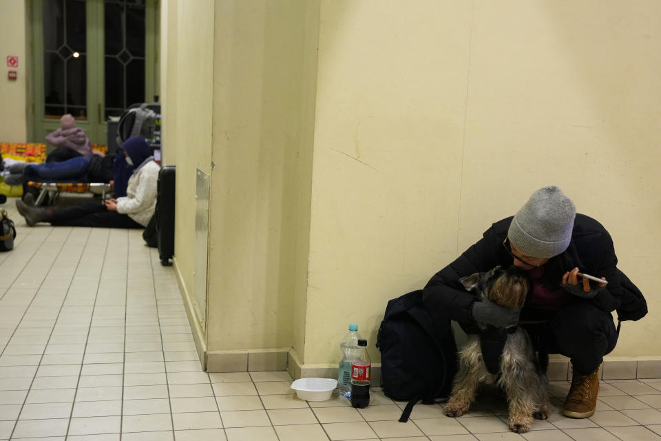 A woman from neighboring Ukraine, sits with her dog at a train station that was turned into an accommodation center in Przemysl, Poland, on Thursday, Feb. 24, 2022. (AP Photo/Petr David Josek)