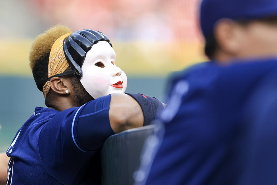 Tampa Bay Rays' Yandy Diaz wears a mask as he watches the team from the dugout during the first inning of a baseball game against the Cincinnati Reds in Cincinnati, Friday, July 8, 2022. (AP Photo/Aaron Doster)