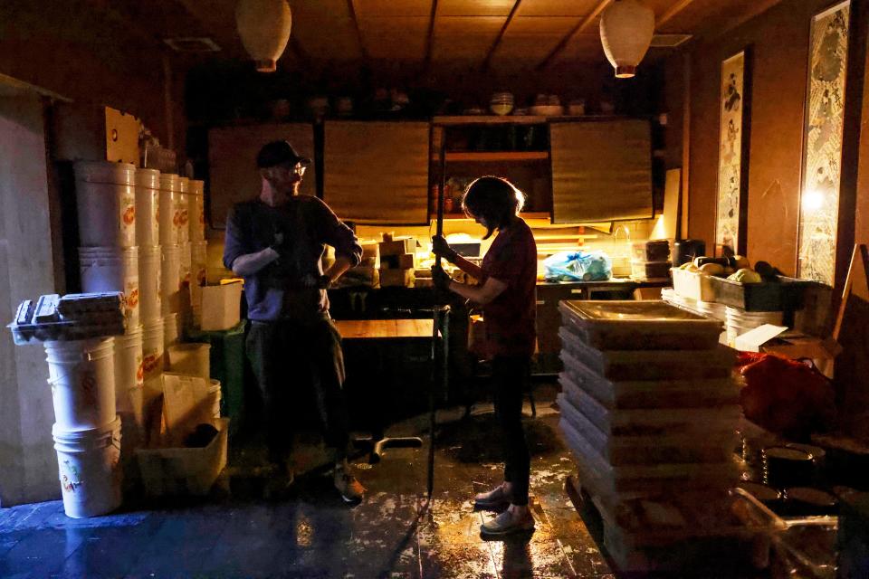 From left, Rintaro employees Aaron Linenberger and Akiko Mochizuki clean up from Saturday's floodwater at the restaurant on New Year's Day in San Francisco.