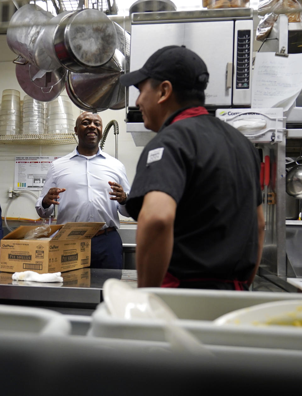 Sen. Tim Scott, R-S.C., talks with a kitchen worker during a visit to the Red Arrow Diner, Thursday, April 13, 2023, in Manchester, N.H. Scott on Wednesday launched an exploratory committee for a 2024 GOP presidential bid, a step that comes just shy of making his campaign official. (AP Photo/Charles Krupa)