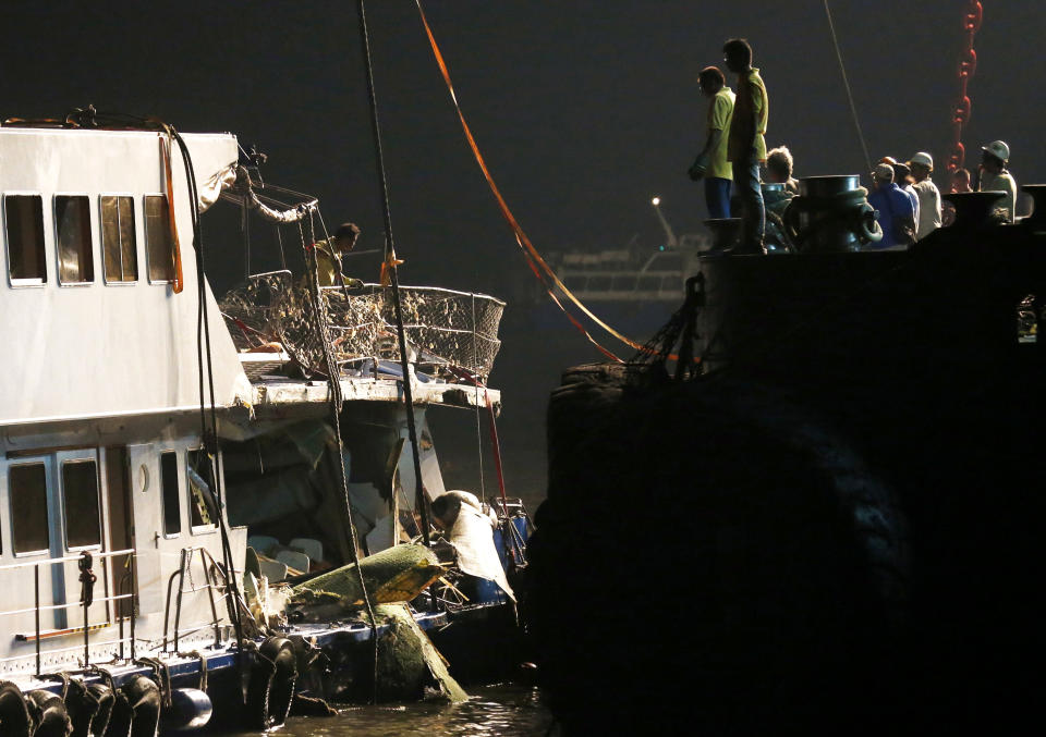 Workers look at a salvaged boat which sank previous night after colliding with a ferry near Lamma Island, off the southwestern coast of Hong Kong Island Tuesday, Oct. 2, 2012. The boat packed with revelers on a long holiday weekend sank, killing nearly 40 people and injuring dozens, authorities said. (AP Photo/Kin Cheung)