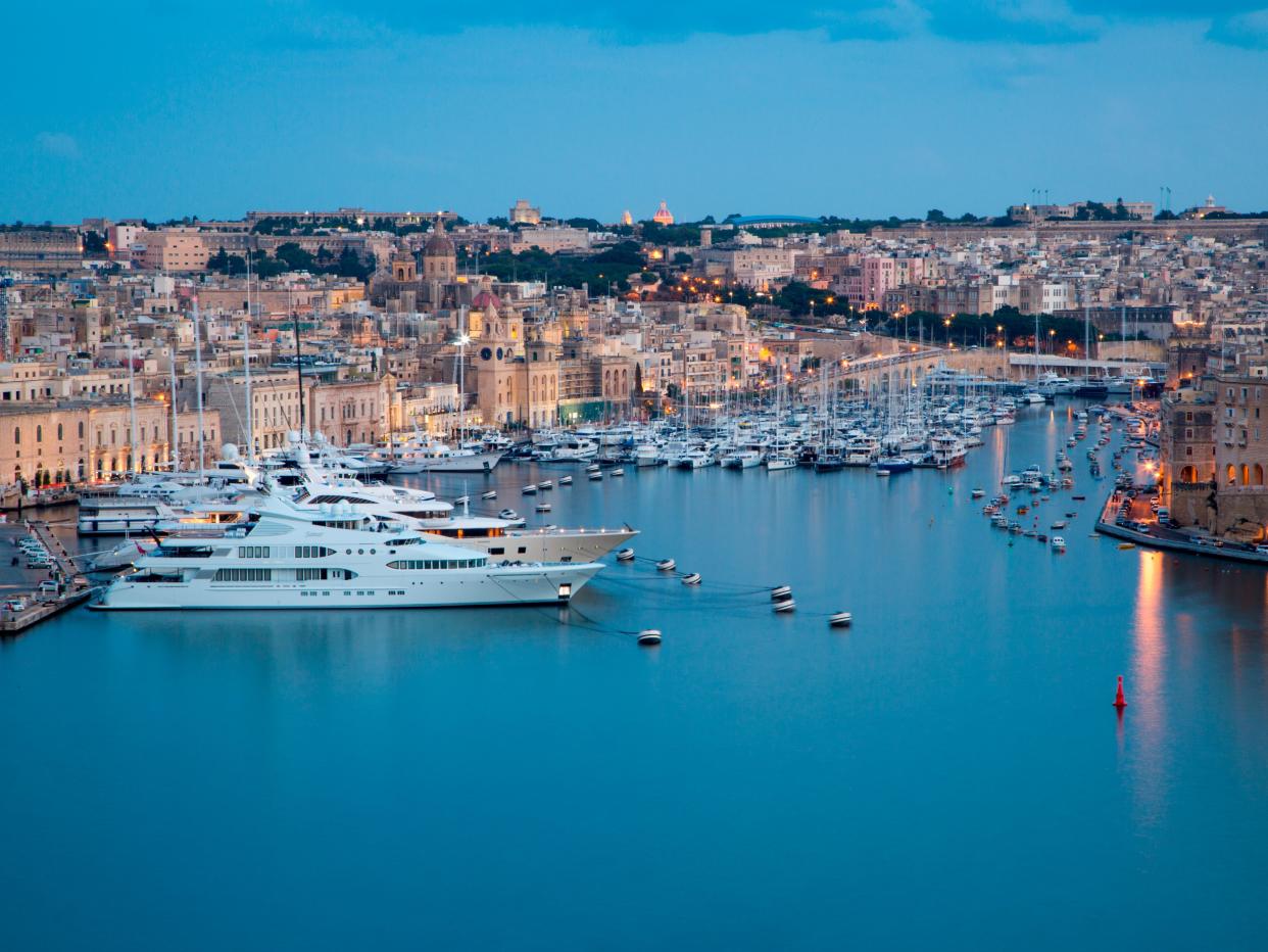 Luxury yachts and sailboats at Kalkara marina with Vittoriosa on right seen from Upper Barrakka Gardens at dusk, Valletta, Malta.