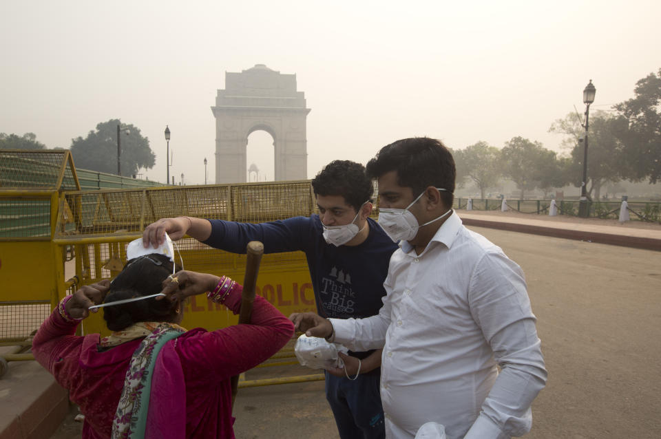 Indians helps to put a mask a day after Diwali festival, in New Delhi, India, Thursday, Nov. 8, 2018. Toxic smog shrouds the Indian capital as air quality falls to hazardous levels with tens of thousands of people setting off massive firecrackers to celebrate the major Hindu festival of Diwali on Wednesday night. (AP Photo/Manish Swarup)