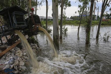 A man looks on as water is pumped out of a canal near 304 Industrial Estate at Srimahaphot district in Prachin Buri September 29, 2013. REUTERS/Athit Perawongmetha