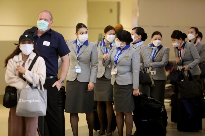 LOS ANGELES, CA - DECEMBER 3, 2021 - Travelers and a flight crew wait in at the Tom Bradley International Terminal at Los Angeles International Airport Friday, December 3, 2021. Los Angeles reported its first case of a person infected with the Omicron variant on Thursday, December 2. In partnership with the state and U.S. Centers for Disease Control and Prevention, the county set up a free rapid testing site for arriving passengers. (Genaro Molina / Los Angeles Times)