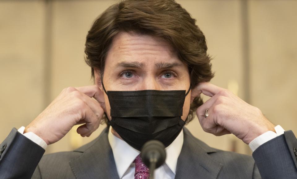 Canadian Prime Minister Justin Trudeau removes his mask as he arrives at a news conference on Monday, Feb. 14 in Ottawa to announce the Emergencies Act will be invoked to deal with protests.