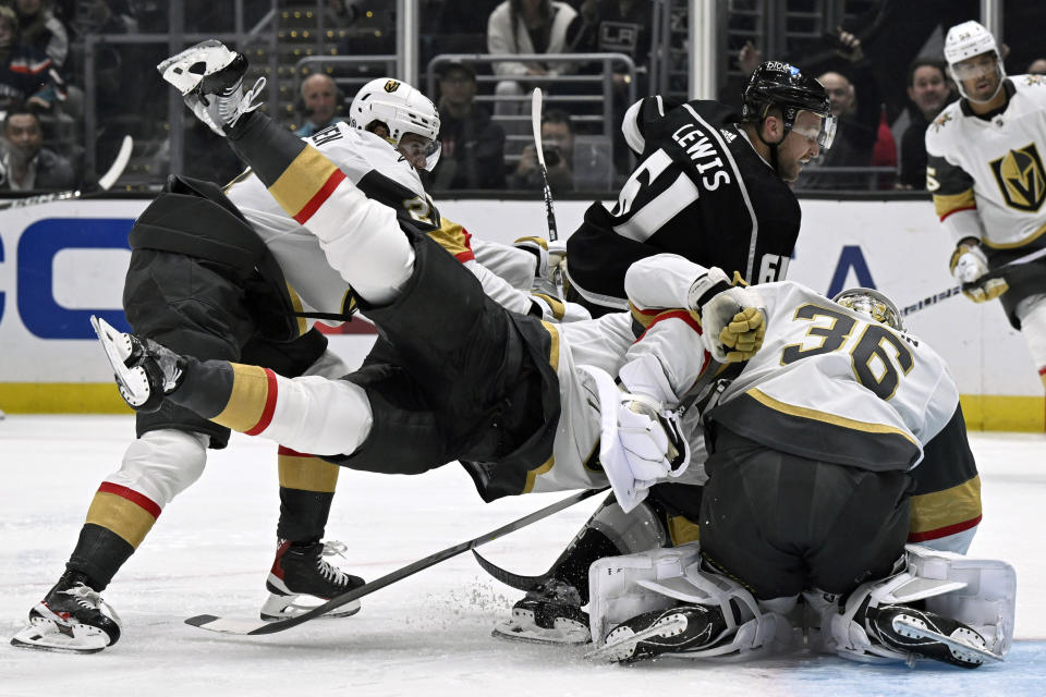 Los Angeles Kings center Trevor Lewis (61) scores as Vegas Golden Knights defenseman Nicolas Hague, center, flips over goaltender Logan Thompson (36) and into center Brett Howden, left, during the second period of an NHL hockey game in Los Angeles, Saturday, Oct. 28, 2023. (AP Photo/Alex Gallardo)