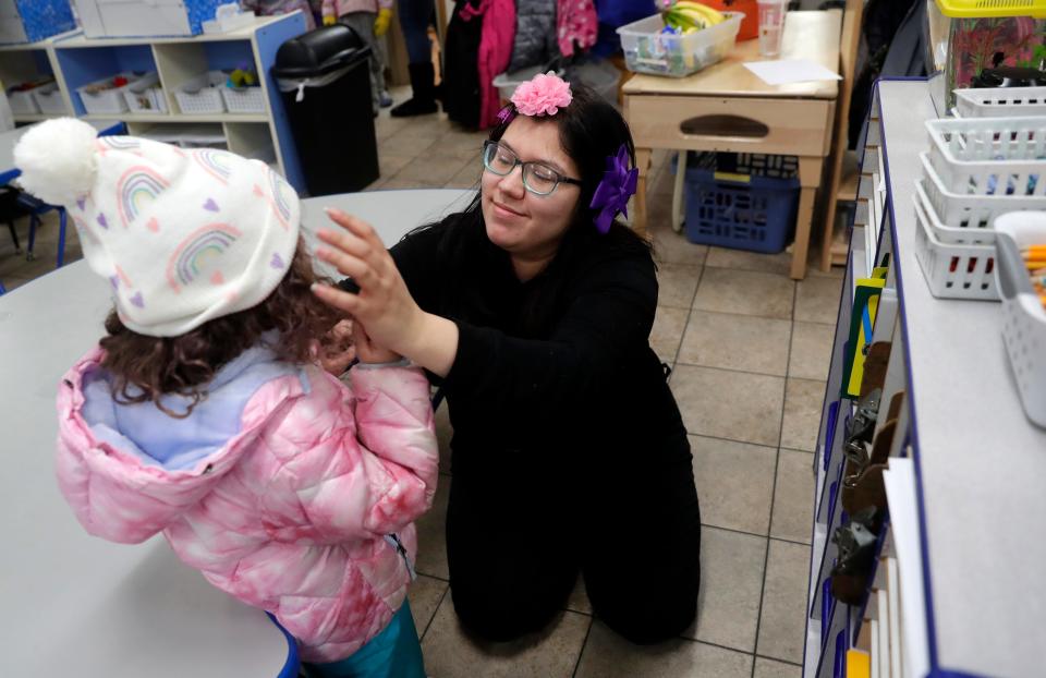 Isabel Meza, teacher at Encompass Early Education & Care's Bellin Health Center, visits her daughter, Anaid, in another classroom and helps her put on winter clothing before the class went to play outside on Feb. 24, 2023, in Allouez, Wis.