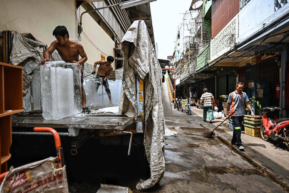 Image: Workers move blocks of ice into a storage unit at a fresh market during heatwave conditions in Bangkok on April 25, 2023. (Lillian Suwanrumpha / AFP - Getty Images)